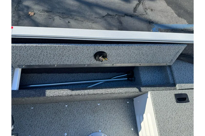 Slide: The Image of 2026 Lund 1650 Angler SS boat storage compartment with fishing rod holder. - 16