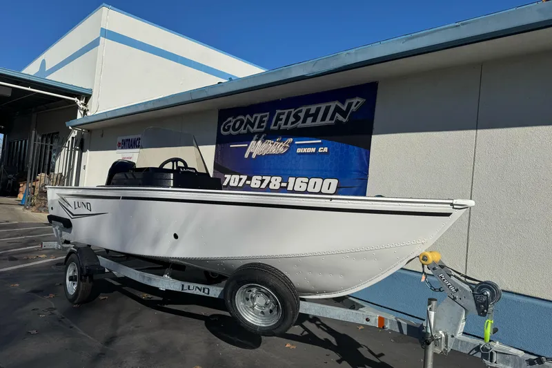 Slide: The Image of 2026 Lund 1650 Angler SS boat on trailer outside dealership, "Gone Fishin'" sign visible. - 6