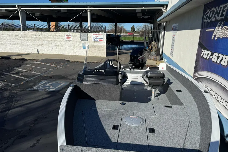 Slide: The Image of 2026 Lund 1650 Angler SS fishing boat with Mercury engine, parked outdoors. - 8