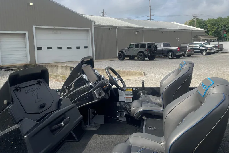 Slide: The Image of 2021 Nitro Z20 boat interior with steering wheel and seats, parked near a garage. - 7