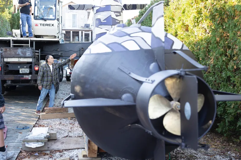 Slide: The Image of 2023 Submarine 28 Composite Construction being transported, with people and equipment nearby. - 5