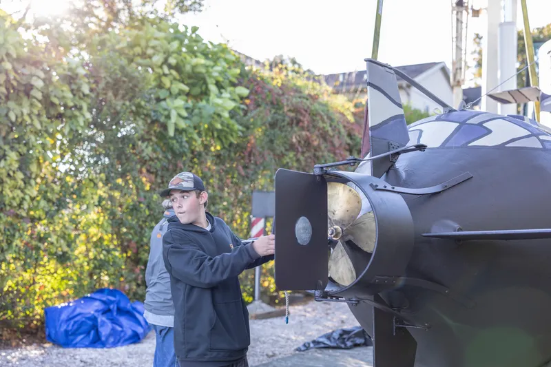 Slide: The Image of Two people inspecting a 2023 Submarine 28 Composite Construction outdoors. - 6