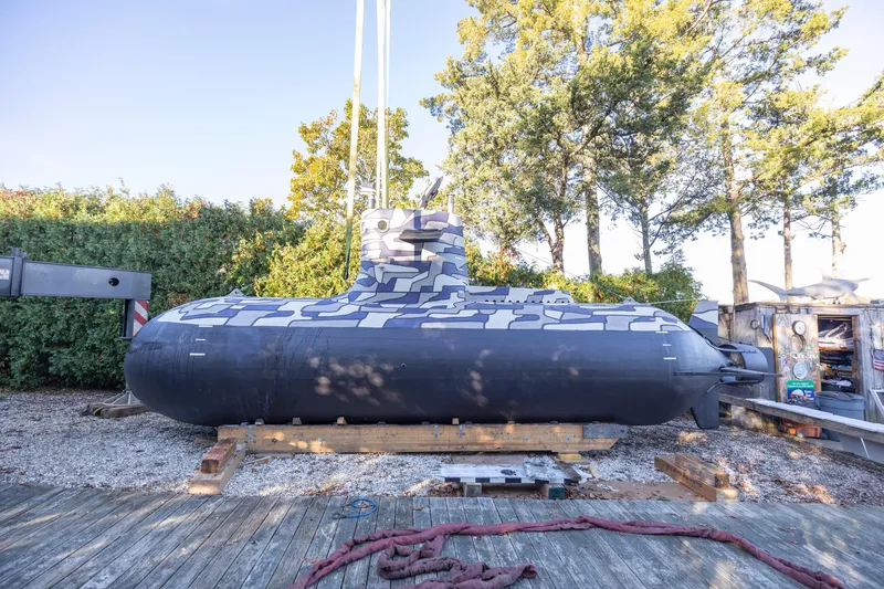 Slide: The Image of 2023 Submarine 28 Composite Construction on land, surrounded by trees and equipment. - 8