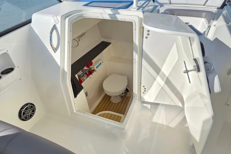 Slide: The Image of 2018 World Cat 280 DC-X boat interior with open door revealing compact marine toilet. - 32