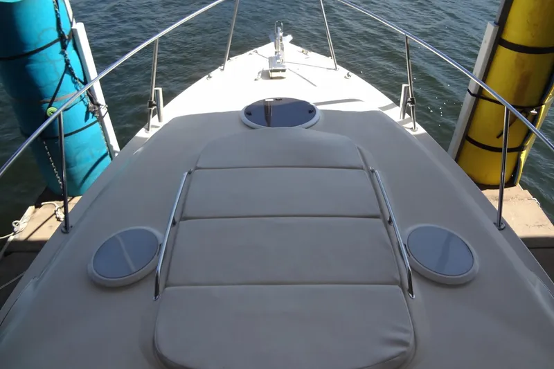 Slide: The Image of 2000 Monterey 302 Cruiser boat deck with cushioned seating, docked by colorful buoys. - 10