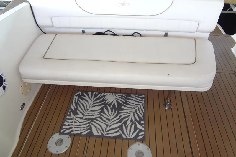 Slide: The Image of White cushioned seating on 2000 Monterey 302 Cruiser boat with teak flooring and decorative rug. - 24