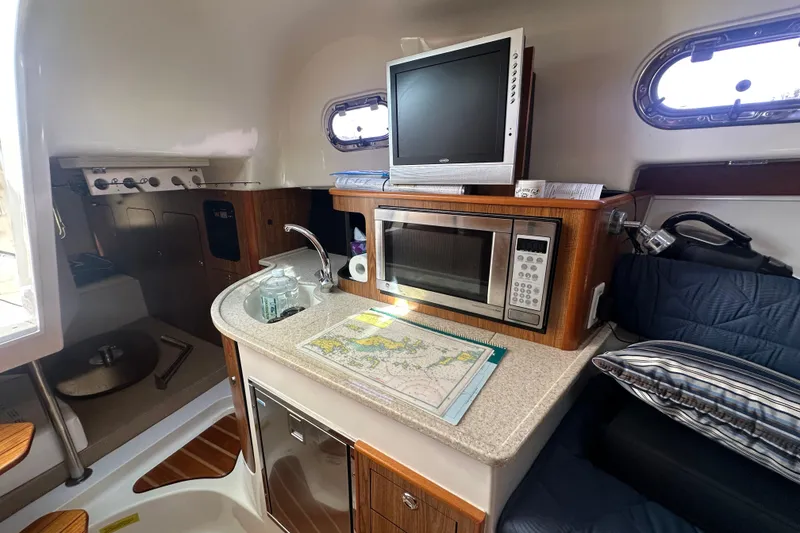 Slide: The Image of 2010 Pursuit OS 315 Offshore cabin with kitchenette, microwave, and TV. - 15