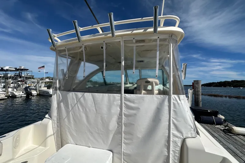 Slide: The Image of 2010 Pursuit OS 315 Offshore boat docked, featuring a covered helm and clear blue sky. - 7