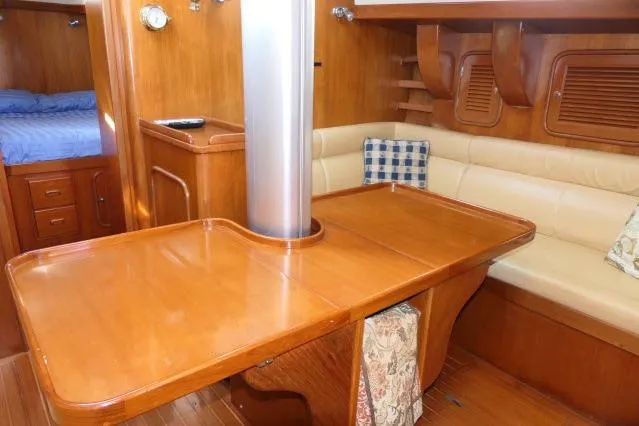 Slide: The Image of 2002 Tayana 460 Vancouver Pilothouse interior with wooden dining area and cushioned seating. - 17
