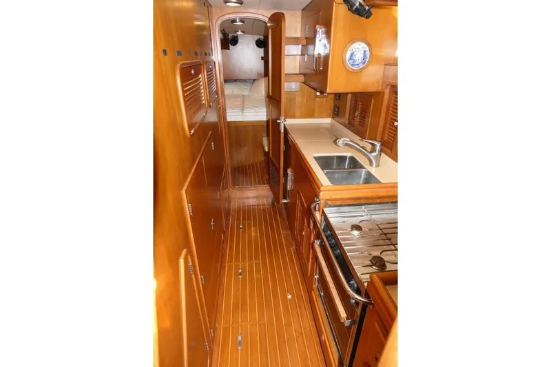 Slide: The Image of 2002 Tayana 460 Vancouver Pilothouse interior with wood finish, kitchen, and sleeping area. - 30