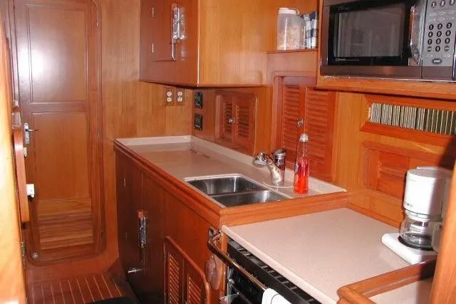 Slide: The Image of 2002 Tayana 460 Vancouver Pilothouse kitchen with wooden cabinetry and modern appliances. - 32
