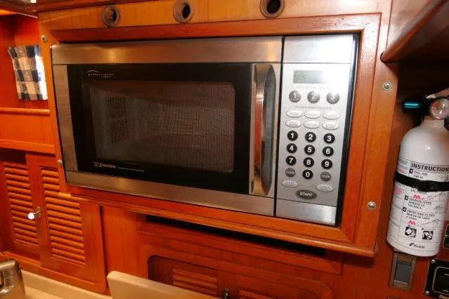 Slide: The Image of Microwave in 2002 Tayana 460 Vancouver Pilothouse kitchen, featuring wooden cabinetry and fire extinguisher. - 37