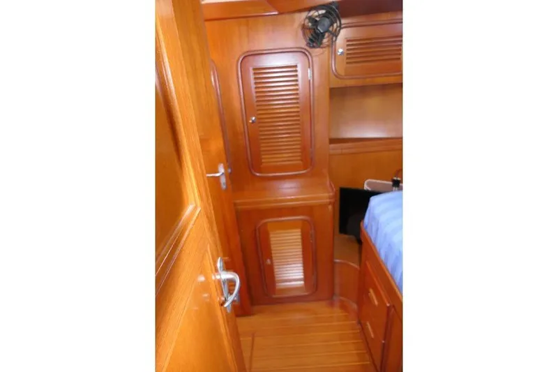 Slide: The Image of Interior of 2002 Tayana 460 Vancouver Pilothouse with wooden cabinetry and blue bedding. - 52
