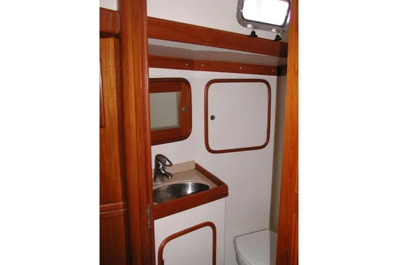Slide: The Image of 2002 Tayana 460 Vancouver Pilothouse bathroom with sink, mirror, and wooden accents. - 55
