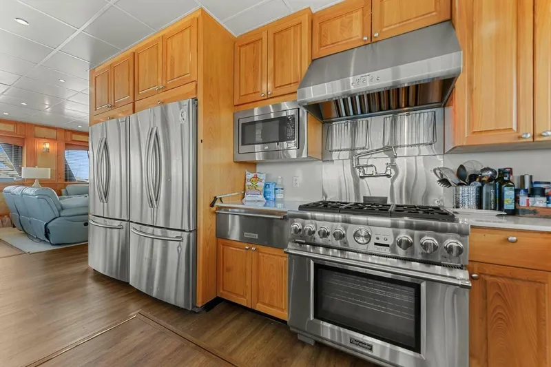 Slide: The Image of Luxurious kitchen in 2018 Avenger Custom Catamaran with stainless steel appliances and wooden cabinetry. - 18