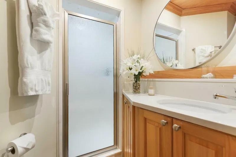 Slide: The Image of Luxurious catamaran bathroom with wooden cabinets, round mirror, and elegant floral decor. - 33