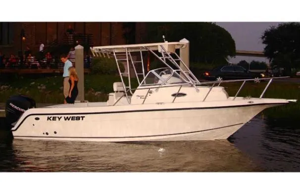 The Image of 2008 Key West 2300 Walkaround boat docked at sunset with two people nearby. - 0