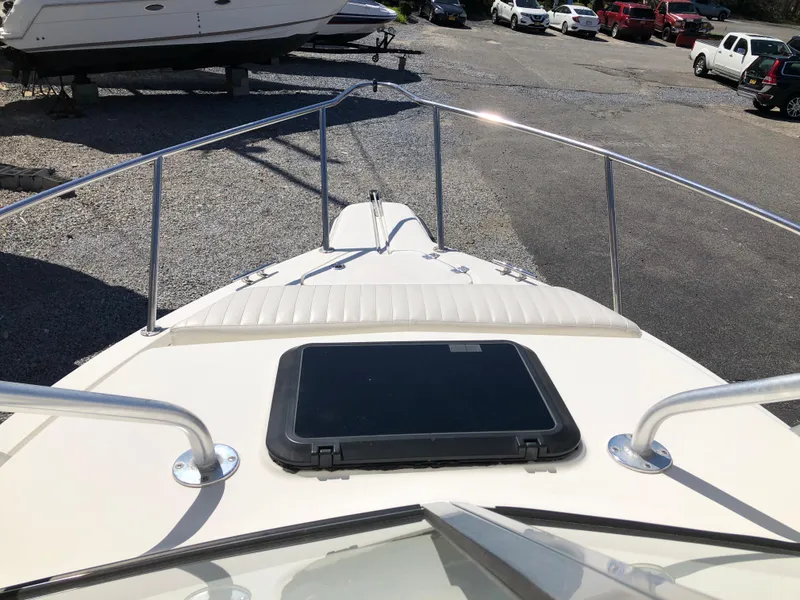 Slide: The Image of 2008 Key West 2300 Walkaround boat deck with railing and hatch, parked on gravel. - 11