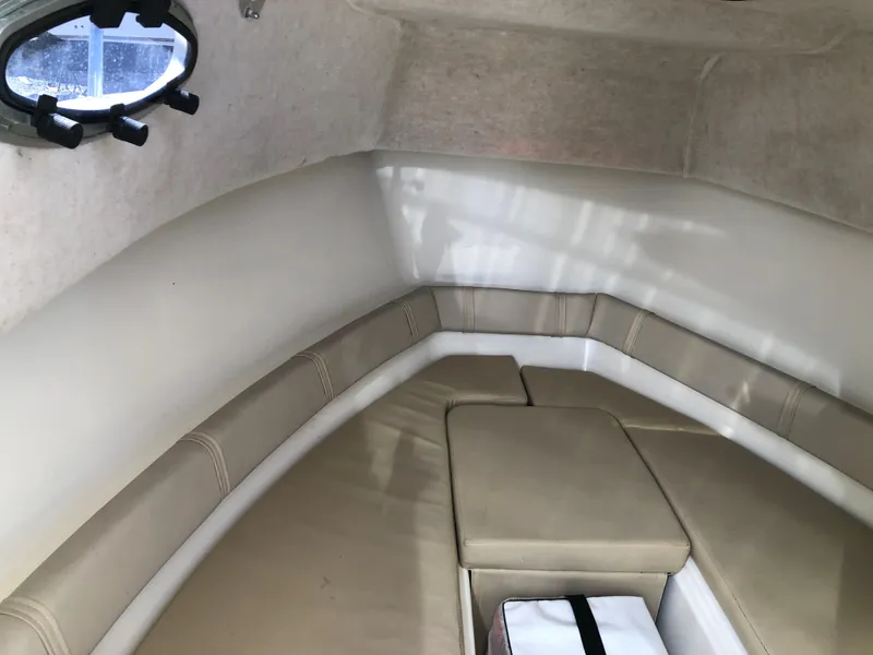 Slide: The Image of 2008 Key West 2300 Walkaround cabin interior with beige seating and porthole window. - 12