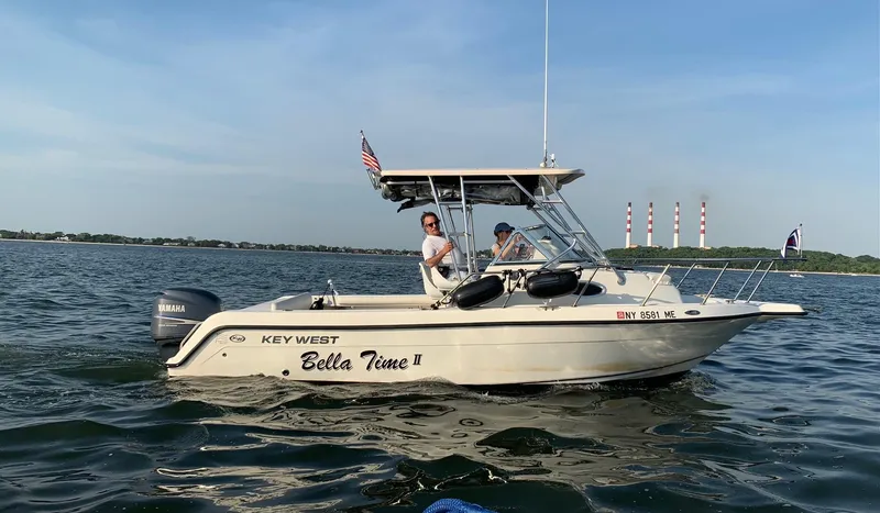Slide: The Image of 2008 Key West 2300 Walkaround boat on water, clear sky, two people onboard. - 6