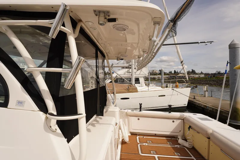 Slide: The Image of 2015 Pursuit OS 385 Offshore boat docked, showcasing deck and fishing rod holders. - 10