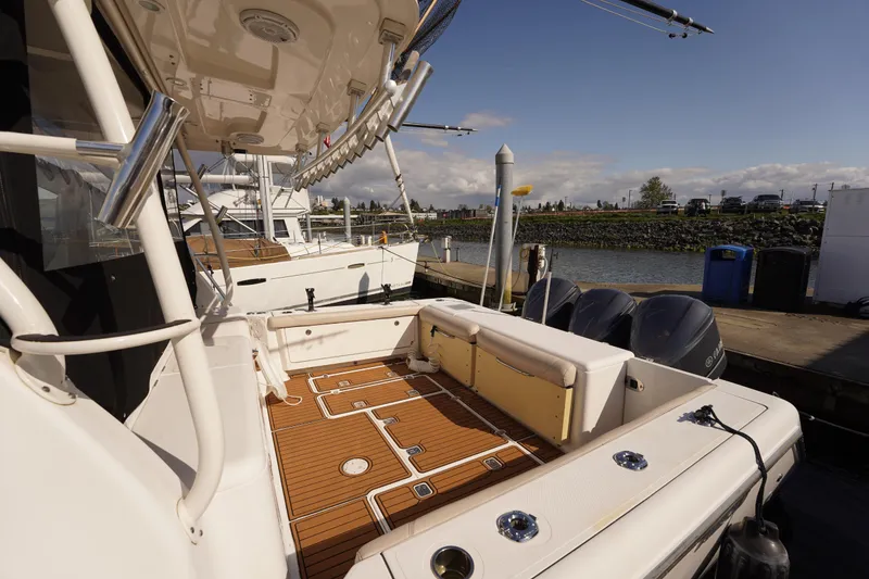 Slide: The Image of 2015 Pursuit OS 385 Offshore boat docked, featuring spacious deck and dual outboard engines. - 14