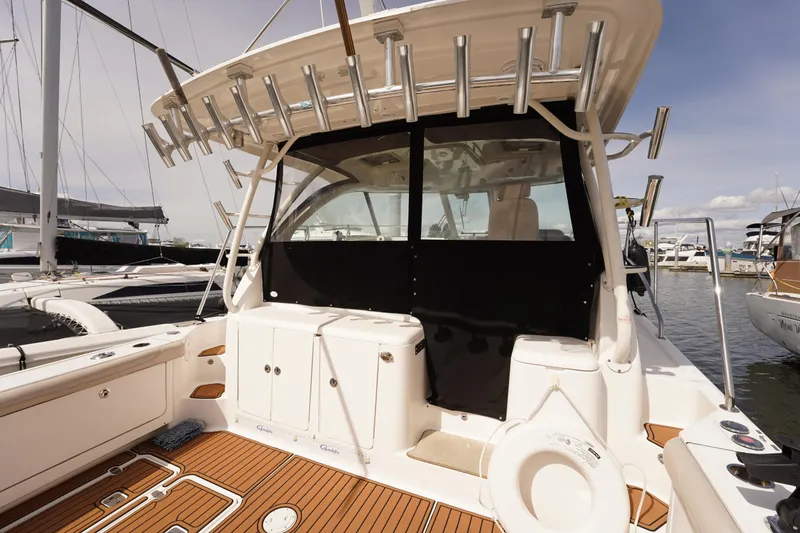Slide: The Image of 2015 Pursuit OS 385 Offshore boat interior with rod holders and teak flooring at marina. - 15