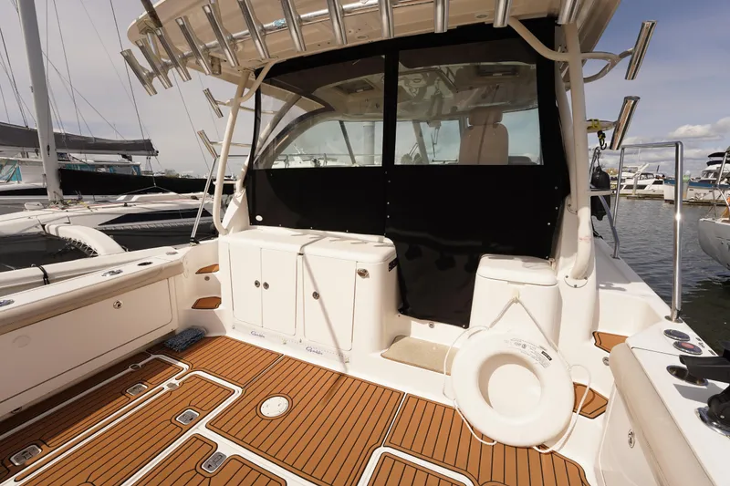 Slide: The Image of 2015 Pursuit OS 385 Offshore boat interior with teak flooring and fishing rod holders. - 16
