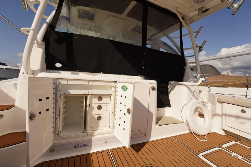 Slide: The Image of 2015 Pursuit OS 385 Offshore boat interior with open storage compartments and teak flooring. - 17