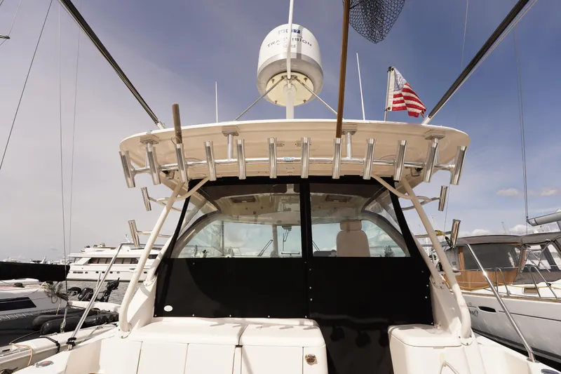 Slide: The Image of 2015 Pursuit OS 385 Offshore boat docked, featuring fishing rod holders and radar equipment. - 18
