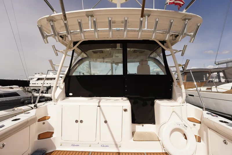 Slide: The Image of 2015 Pursuit OS 385 Offshore boat docked, showcasing spacious cockpit and fishing rod holders. - 19