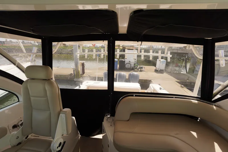 Slide: The Image of Interior view of 2015 Pursuit OS 385 Offshore boat with beige seating and marina backdrop. - 23