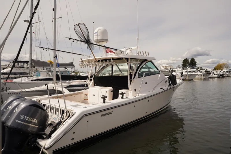 Slide: The Image of 2015 Pursuit OS 385 Offshore boat docked with Yamaha engines, surrounded by other vessels. - 4