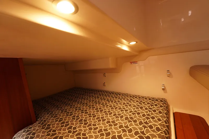 Slide: The Image of 2015 Pursuit OS 385 Offshore cabin interior with patterned bedding and warm lighting. - 44