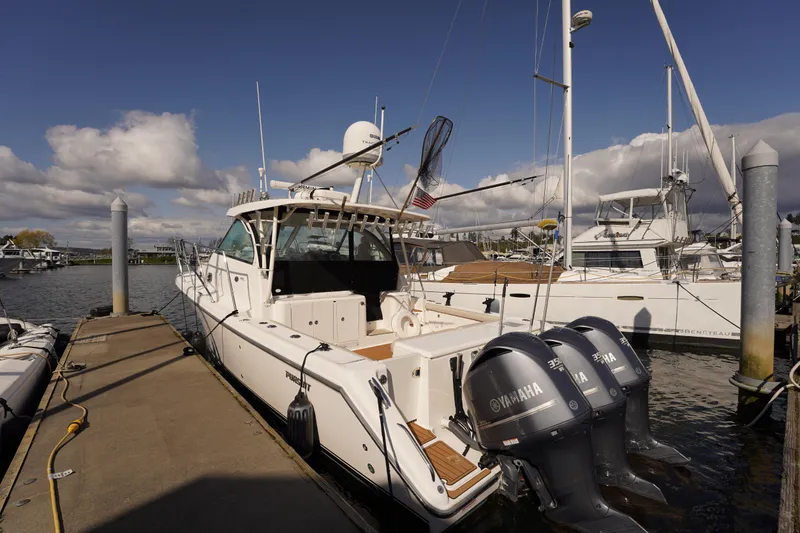 Slide: The Image of 2015 Pursuit OS 385 Offshore boat docked with Yamaha engines, under a partly cloudy sky. - 7