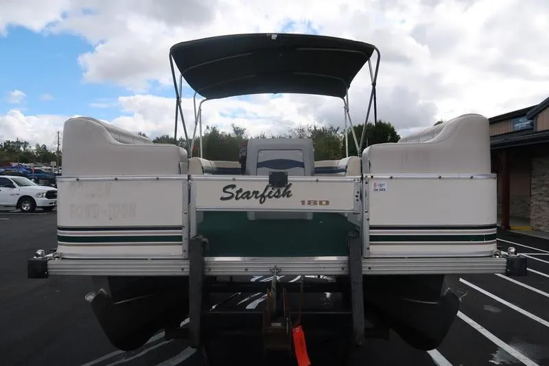Slide: The Image of 1999 Starcraft Starfish 180 pontoon boat, rear view, parked outdoors under cloudy sky. - 12