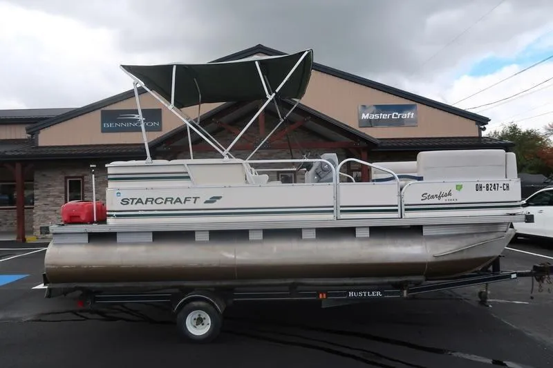 Slide: The Image of 1999 Starcraft Starfish 180 pontoon boat on trailer, parked outside dealership. - 7
