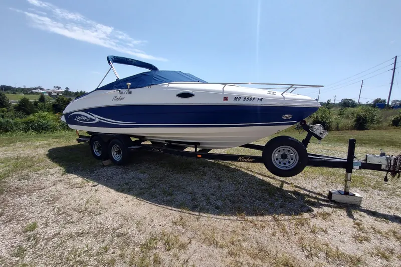 The Image of 2005 Rinker 232 Captiva Cuddy boat on trailer in sunny outdoor setting. - 0