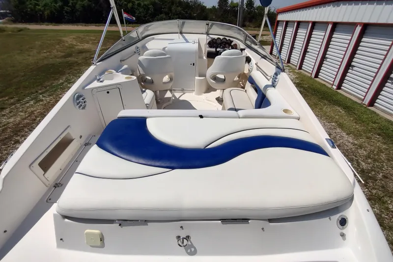 Slide: The Image of 2005 Rinker 232 Captiva Cuddy boat interior with white and blue seating, near storage units. - 1