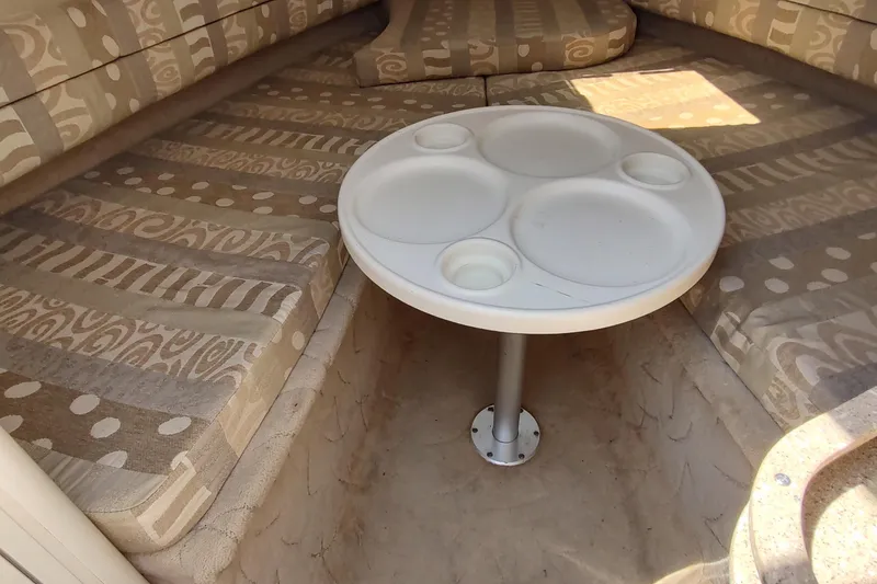 Slide: The Image of 2005 Rinker 232 Captiva Cuddy interior with patterned seating and round table. - 12