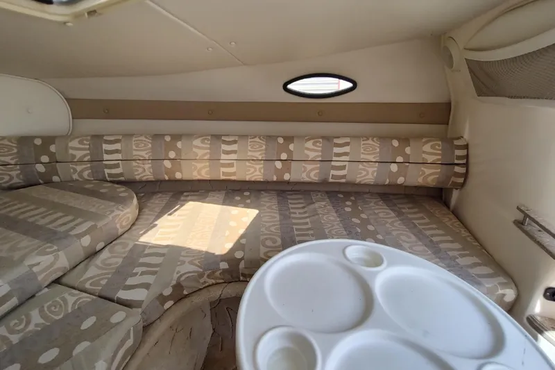 Slide: The Image of 2005 Rinker 232 Captiva Cuddy cabin interior with patterned seating and small table. - 13