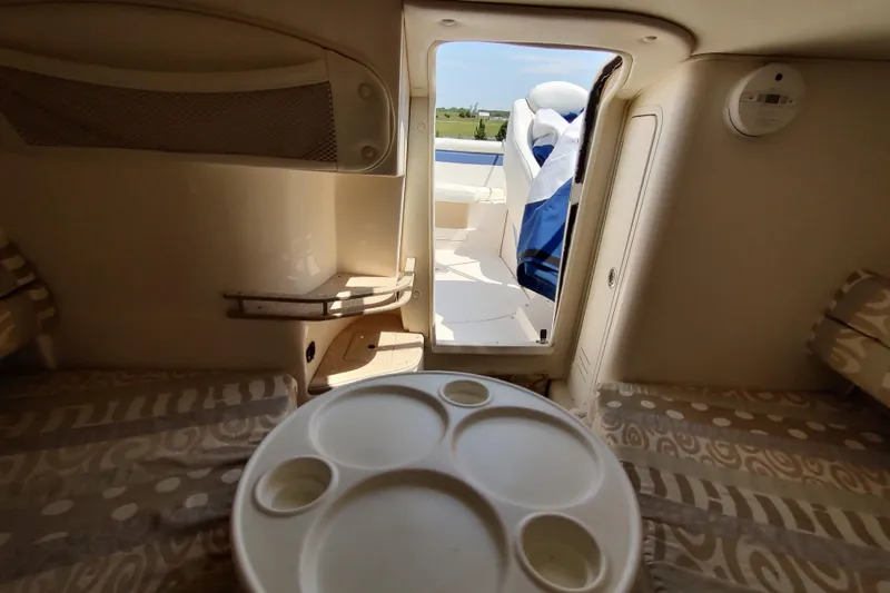 Slide: The Image of 2005 Rinker 232 Captiva Cuddy cabin interior with seating and table, open door to deck. - 14