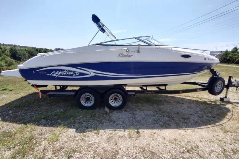 Slide: The Image of 2005 Rinker 232 Captiva Cuddy boat on trailer, parked on grassy area. - 17