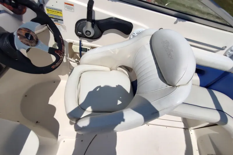 Slide: The Image of 2005 Rinker 232 Captiva Cuddy boat interior with steering wheel and white captain's seat. - 8