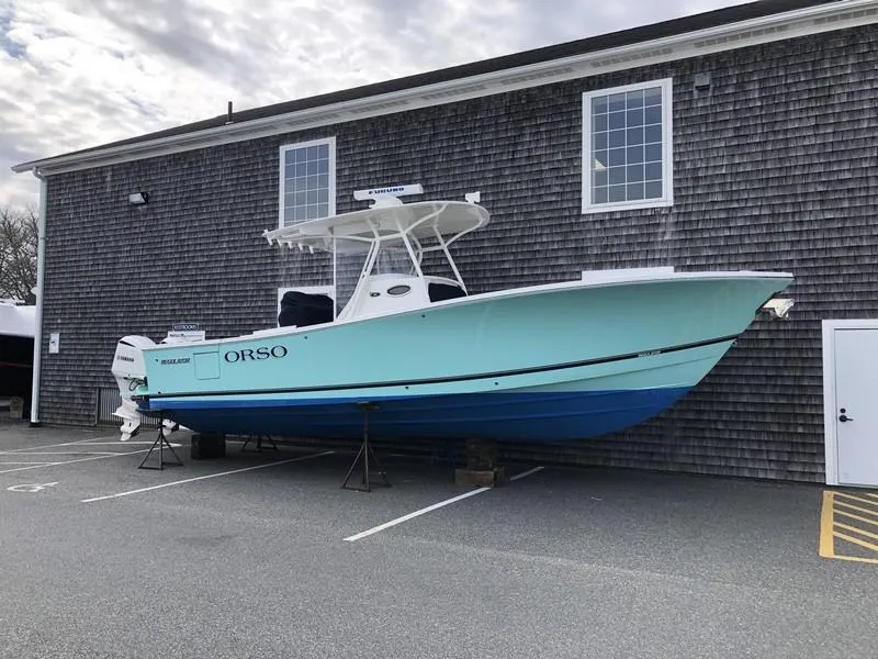 Slide: The Image of 2018 Regulator 31 boat on stands, parked beside a wooden building. - 5