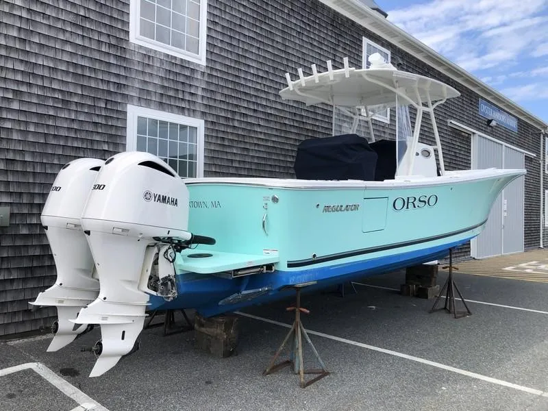 Slide: The Image of 2018 Regulator 31 boat with twin Yamaha engines, docked near a wooden building. - 7