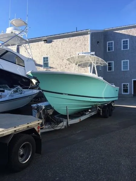 Slide: The Image of 2018 Regulator 31 boat on trailer, light blue hull, parked near a building. - 1