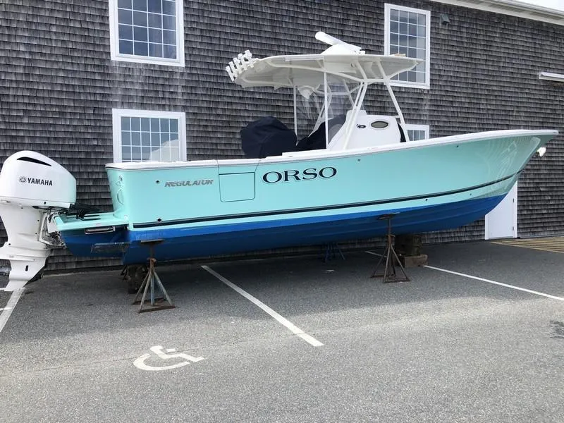 Slide: The Image of 2018 Regulator 31 boat with Yamaha engine, parked on stands near a building. - 6