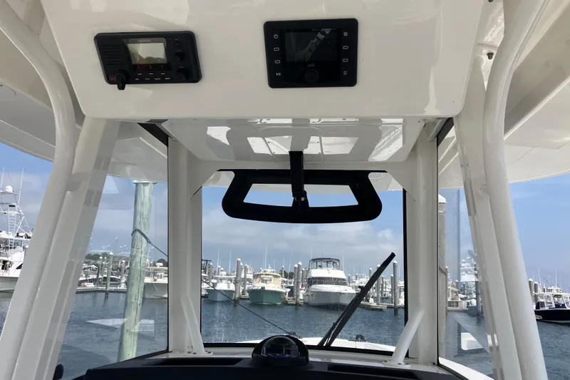 Slide: The Image of 2020 Regulator 31 boat helm with electronics, docked at marina with yachts in background. - 18