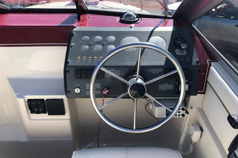 Slide: The Image of Steering wheel and dashboard of a 1992 Maxum 2300 SC boat, featuring control panels. - 12